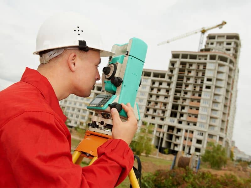 Land surveyor using a total station at a commercial construction site during an ALTA Survey and boundary review process.